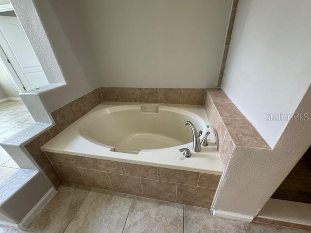 bathroom with tiled bath and tile patterned flooring