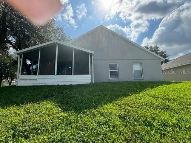 back of house featuring a lawn and a sunroom