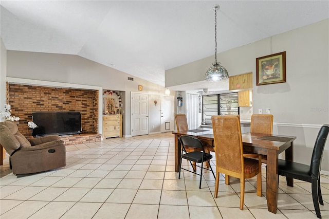 dining area featuring light tile patterned flooring, brick wall, and vaulted ceiling