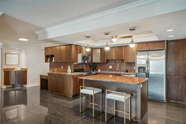 kitchen featuring appliances with stainless steel finishes, backsplash, decorative light fixtures, a center island, and ornamental molding