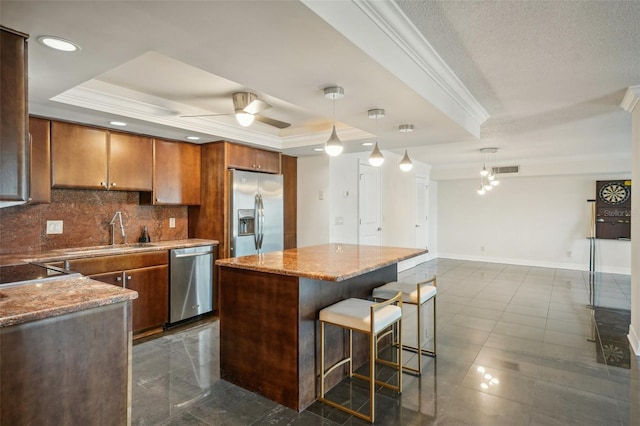 kitchen featuring a sink, a raised ceiling, appliances with stainless steel finishes, and ornamental molding