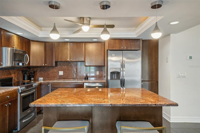 kitchen with a tray ceiling, tasteful backsplash, appliances with stainless steel finishes, and ornamental molding