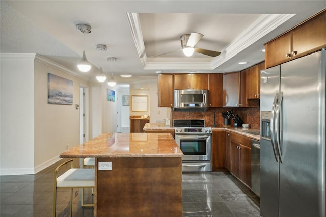 kitchen featuring tasteful backsplash, a center island, crown molding, appliances with stainless steel finishes, and a raised ceiling