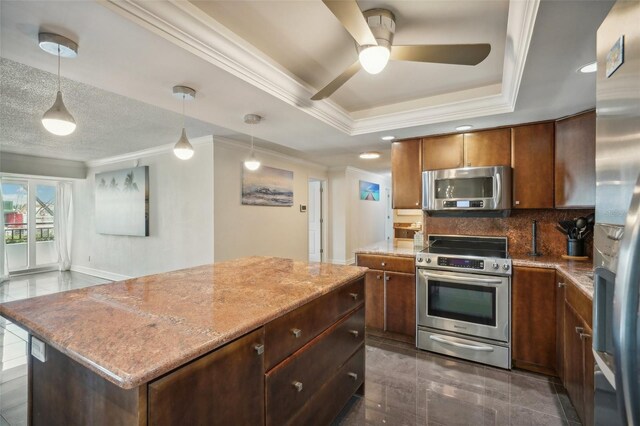 kitchen with stainless steel appliances, crown molding, a center island, ceiling fan, and a raised ceiling