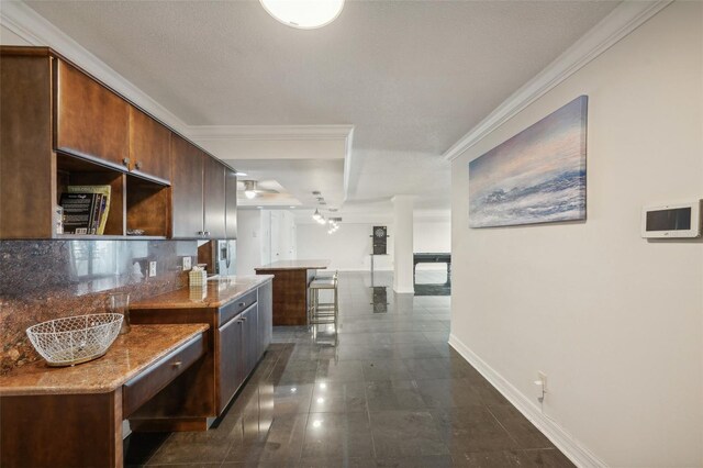 kitchen featuring decorative backsplash, dark tile patterned floors, ornamental molding, and light stone counters