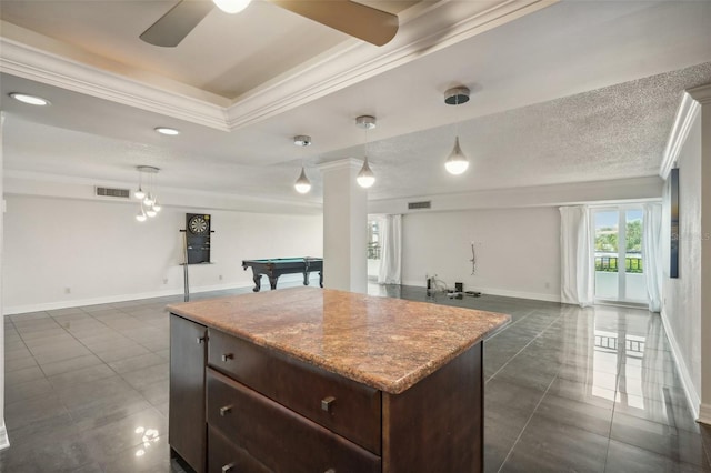 kitchen with visible vents, a kitchen island, dark brown cabinetry, open floor plan, and ornamental molding