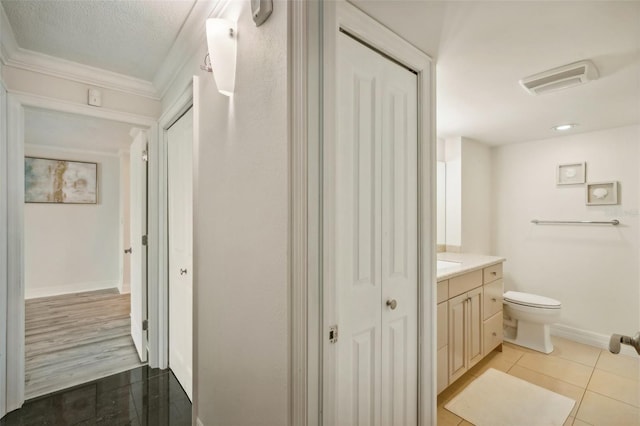 bathroom with crown molding, a textured ceiling, tile patterned floors, toilet, and vanity