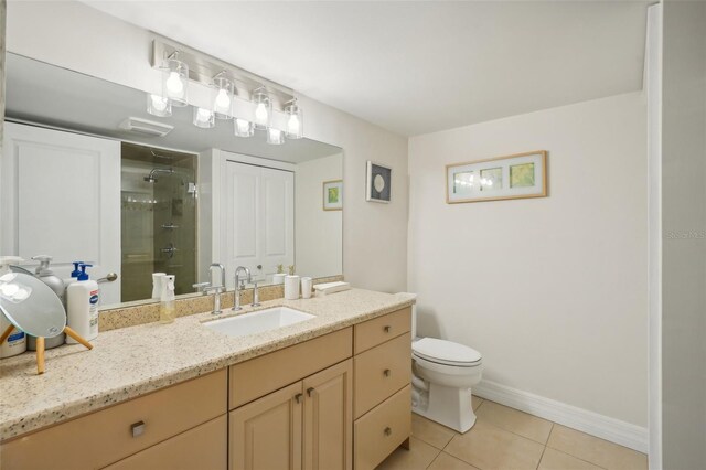 bathroom with tiled shower, vanity, toilet, and tile patterned floors