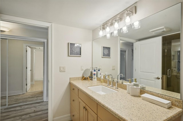 full bathroom with vanity, a shower stall, wood finished floors, and baseboards