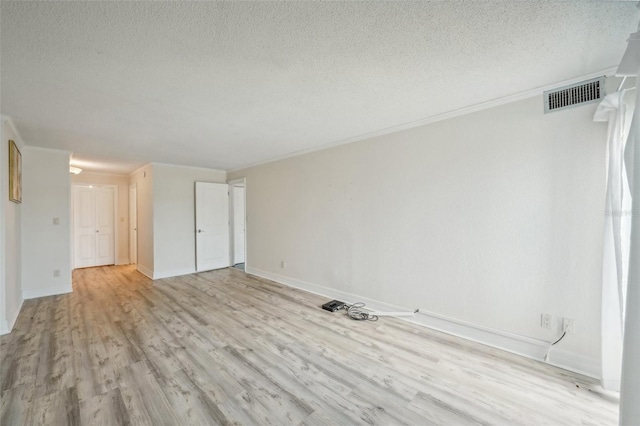 unfurnished room with baseboards, visible vents, light wood-style flooring, a textured ceiling, and crown molding