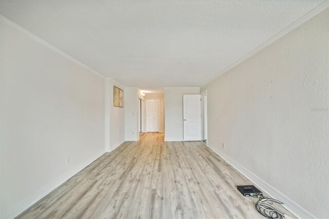 spare room with light hardwood / wood-style flooring, ornamental molding, and a textured ceiling