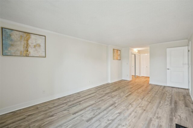 empty room featuring wood-type flooring and ornamental molding