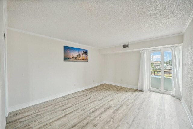 spare room with light wood-type flooring, ornamental molding, and a textured ceiling