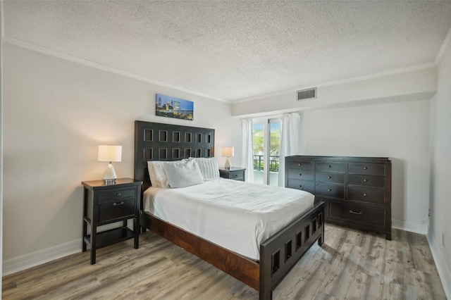 bedroom featuring light wood-style flooring, visible vents, and a textured ceiling