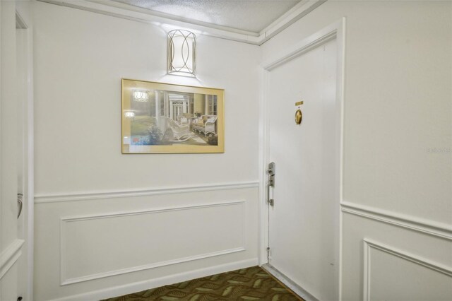 doorway to outside featuring ornamental molding and a textured ceiling