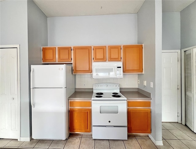 kitchen with white appliances, backsplash, and light tile patterned floors