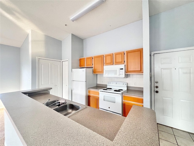 kitchen featuring white appliances, backsplash, light tile patterned floors, and sink