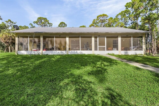 rear view of property with a sunroom and a lawn