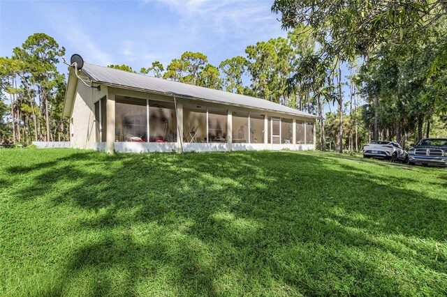 rear view of house with a sunroom and a yard