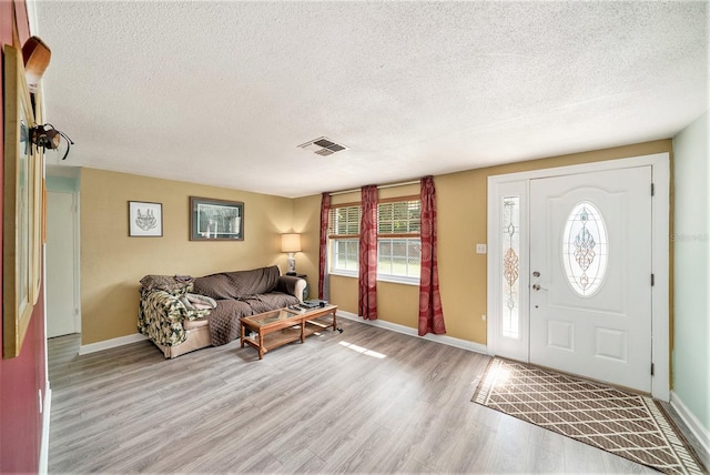 foyer entrance with light hardwood / wood-style flooring and a textured ceiling