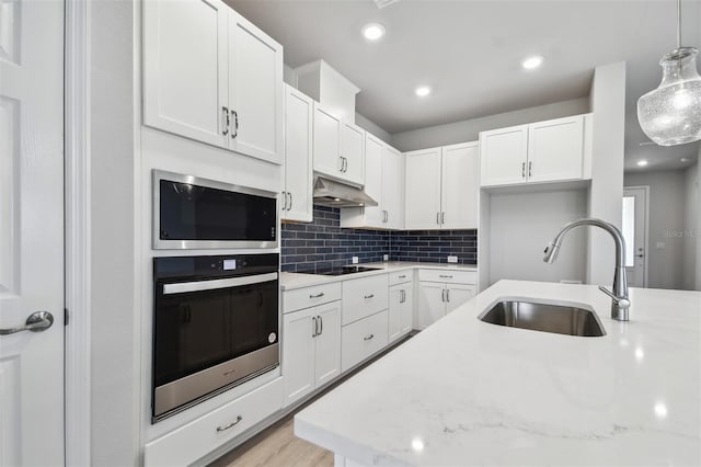 kitchen with sink, hanging light fixtures, stainless steel appliances, light stone countertops, and white cabinets