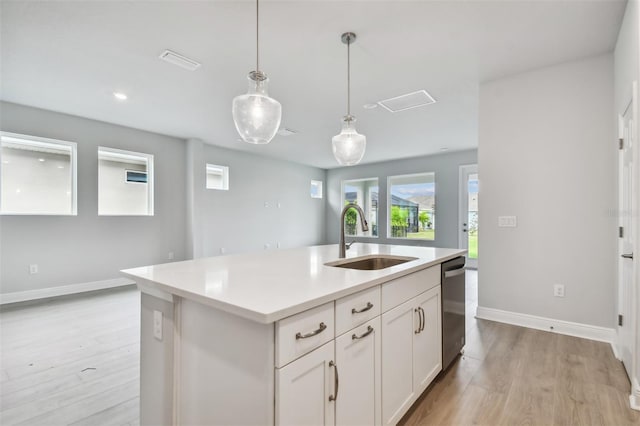 kitchen featuring decorative light fixtures, white cabinetry, sink, a kitchen island with sink, and stainless steel dishwasher