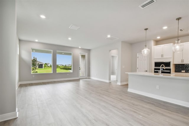 unfurnished living room with sink and light hardwood / wood-style flooring