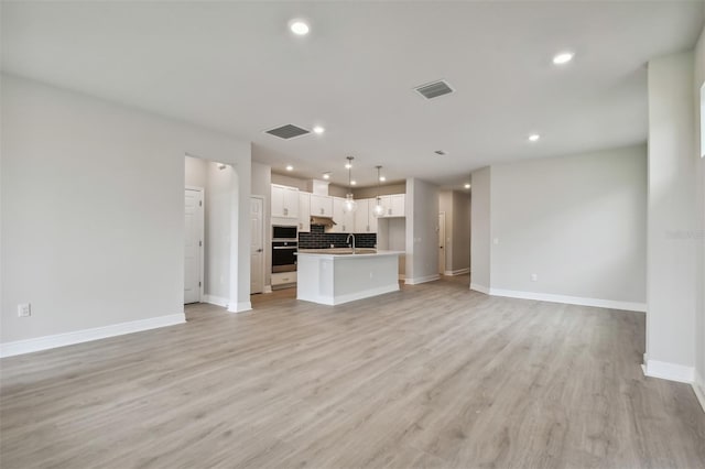 unfurnished living room featuring sink and light wood-type flooring