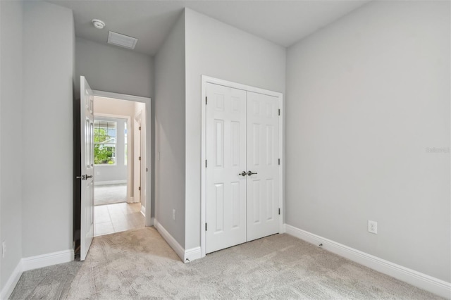 unfurnished bedroom featuring light carpet and a closet