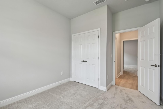 unfurnished bedroom with light colored carpet and a closet