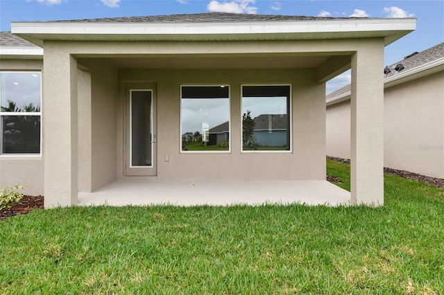 doorway to property with a lawn and a patio