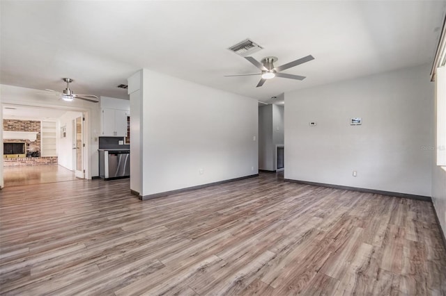 unfurnished living room with a brick fireplace, ceiling fan, and light hardwood / wood-style floors