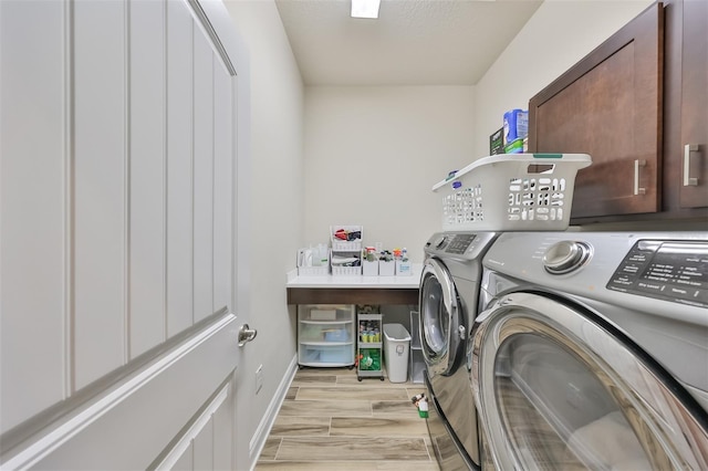 laundry area with cabinets, washing machine and dryer, and light hardwood / wood-style flooring