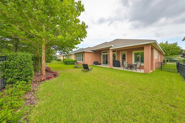 back of property with a yard and a patio area