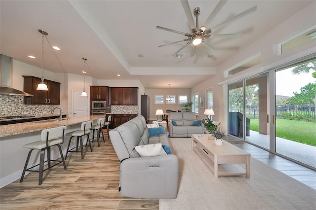 living room featuring sink, ceiling fan, and light hardwood / wood-style flooring