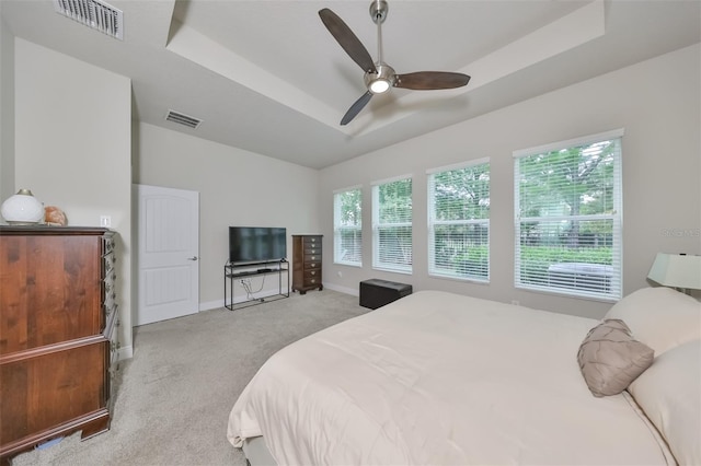 carpeted bedroom featuring a raised ceiling and ceiling fan