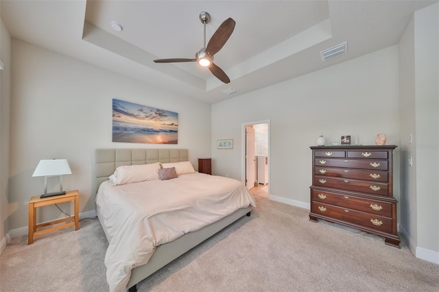 carpeted bedroom featuring a tray ceiling and ceiling fan