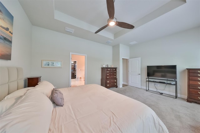 bedroom with a tray ceiling, light colored carpet, and ceiling fan