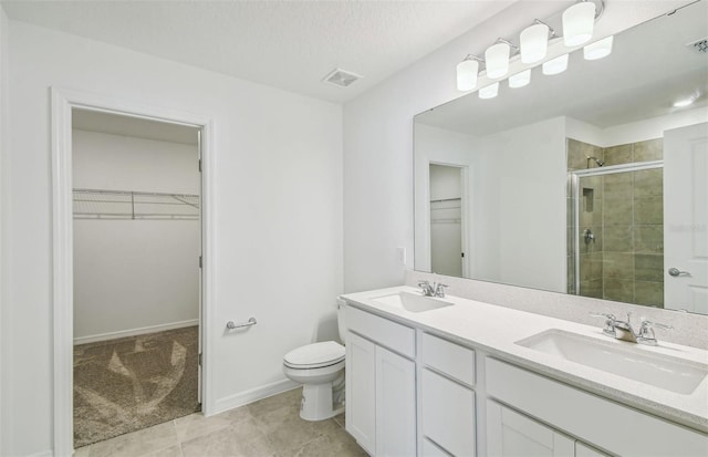 bathroom featuring a shower with door, a textured ceiling, toilet, vanity, and tile patterned flooring