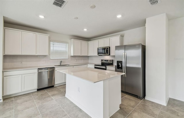 kitchen with a kitchen island, decorative backsplash, sink, white cabinetry, and appliances with stainless steel finishes