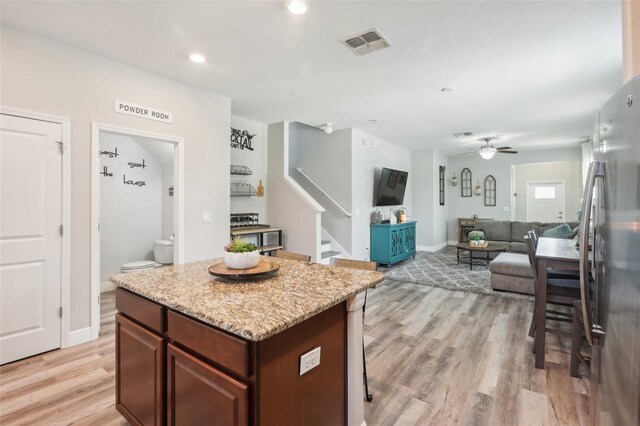 kitchen with light hardwood / wood-style flooring, stainless steel refrigerator, a center island, and ceiling fan