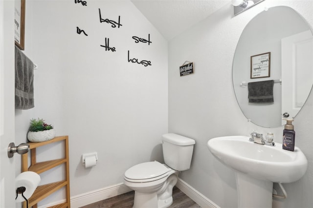 bathroom with wood-type flooring, lofted ceiling, and toilet