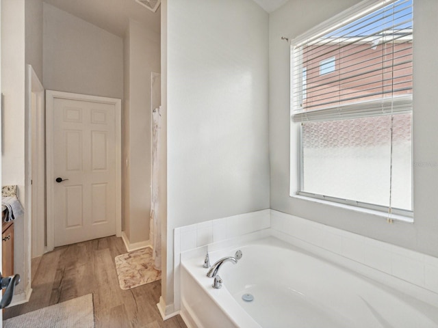 bathroom featuring hardwood / wood-style flooring, a tub to relax in, and vanity