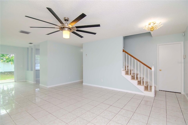 tiled empty room with ceiling fan and a textured ceiling