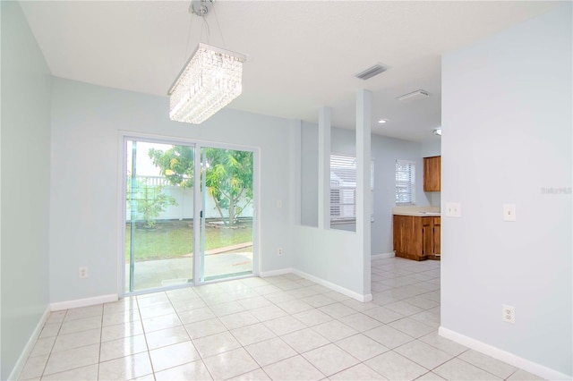 tiled empty room featuring a notable chandelier