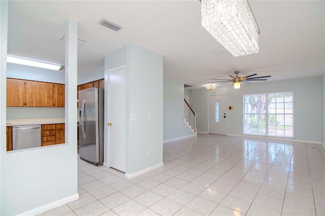 empty room featuring ceiling fan with notable chandelier and light tile patterned floors