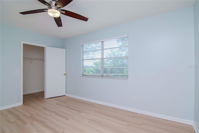 unfurnished bedroom with ceiling fan, a closet, light hardwood / wood-style flooring, and a walk in closet