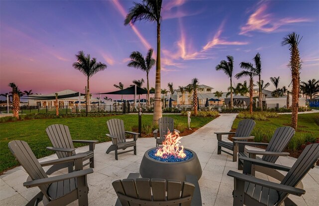 patio terrace at dusk featuring a lawn and an outdoor fire pit