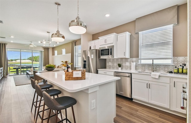 kitchen with tasteful backsplash, white cabinetry, appliances with stainless steel finishes, a center island, and light hardwood / wood-style floors