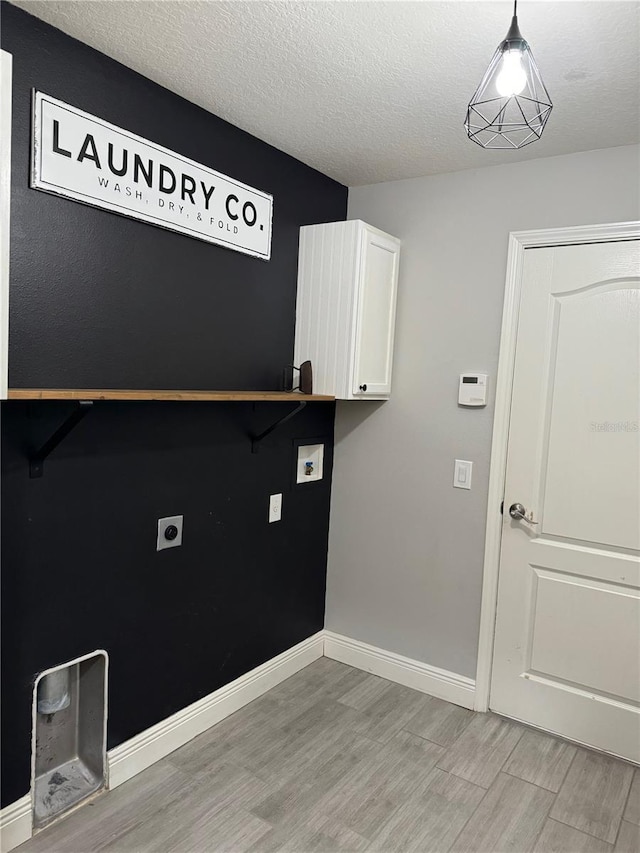 laundry room with electric dryer hookup, light wood-type flooring, a textured ceiling, and cabinets